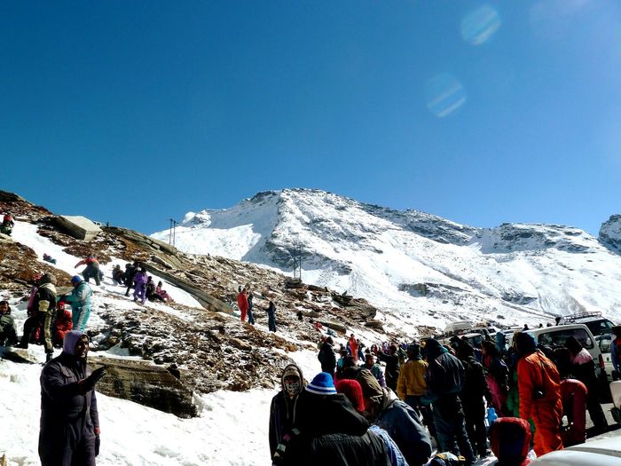 People on snowcapped mountains against clear blue sky