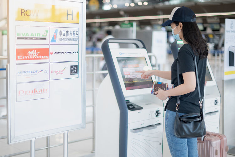 Female hand using the auto self-service check-in for the boarding pass at the airport.