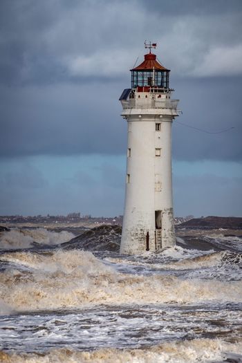 Lighthouse by sea against sky