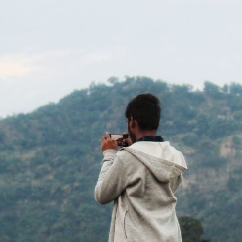 Rear view of man photographing against sky