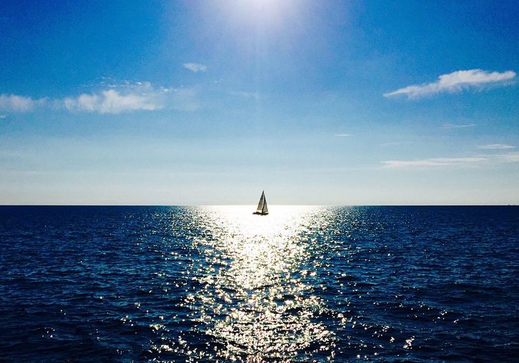 Scenic view of sea against sky with a sailing boat in the center 