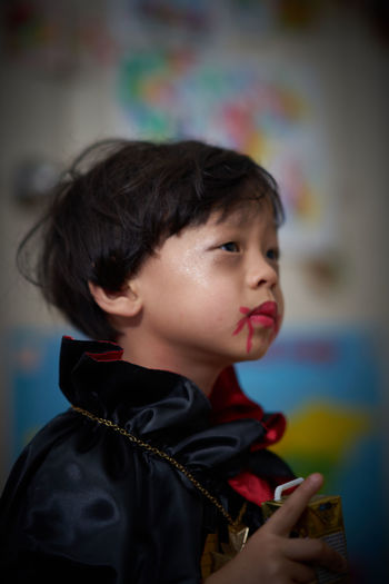 Cute boy with dracula costume looking away