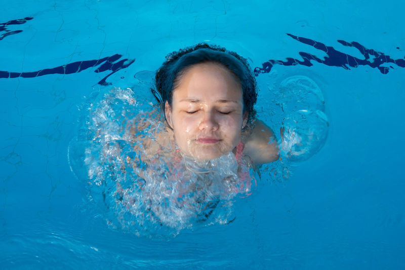 Young girl face popping out of pool