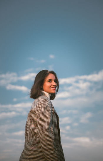 Portrait of young woman standing against sky during sunset