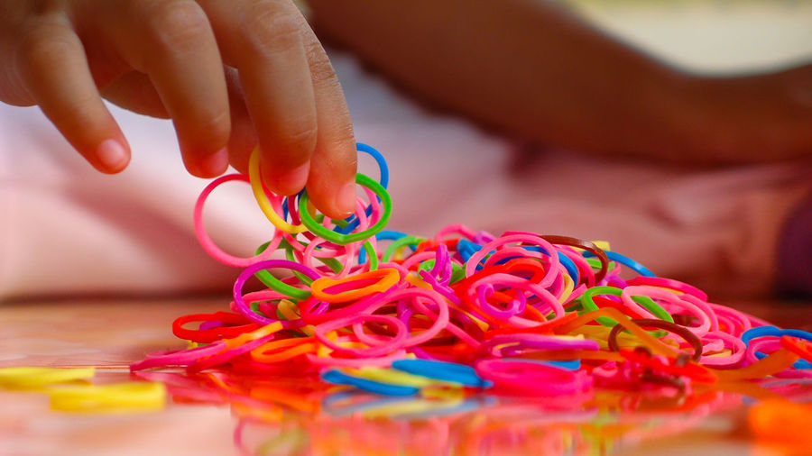 Cropped image of hand holding multi colored rubber band