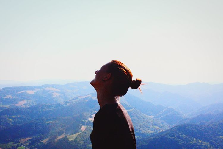 Side view of woman at mountains against clear sky