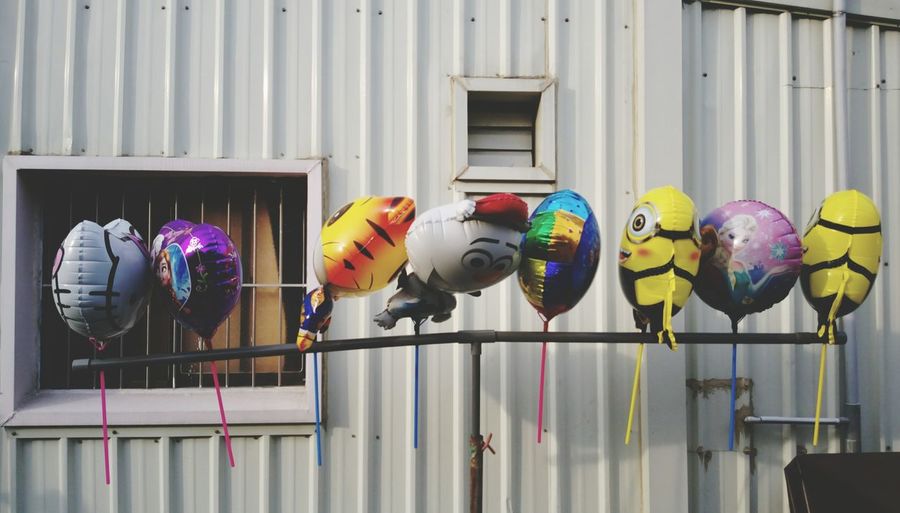 Colorful balloons hanging to pole against house
