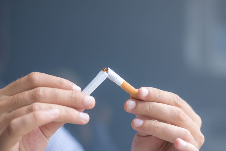 Cropped image of hands breaking cigarette
