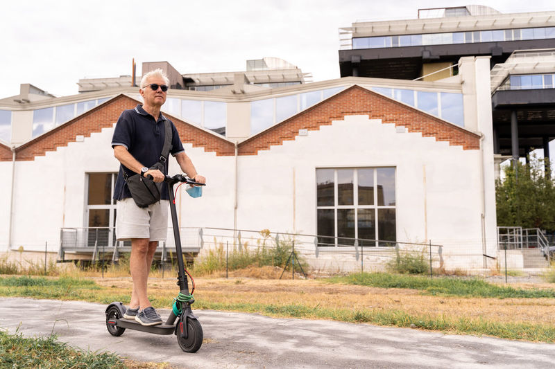 Commuter hipster man is using electric scooter on the outskirts of a city. eco transport concept