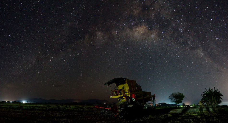 Agricultural machinery on field against sky at night