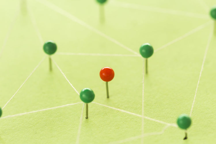 Close-up of strings connected with green straight pins on table