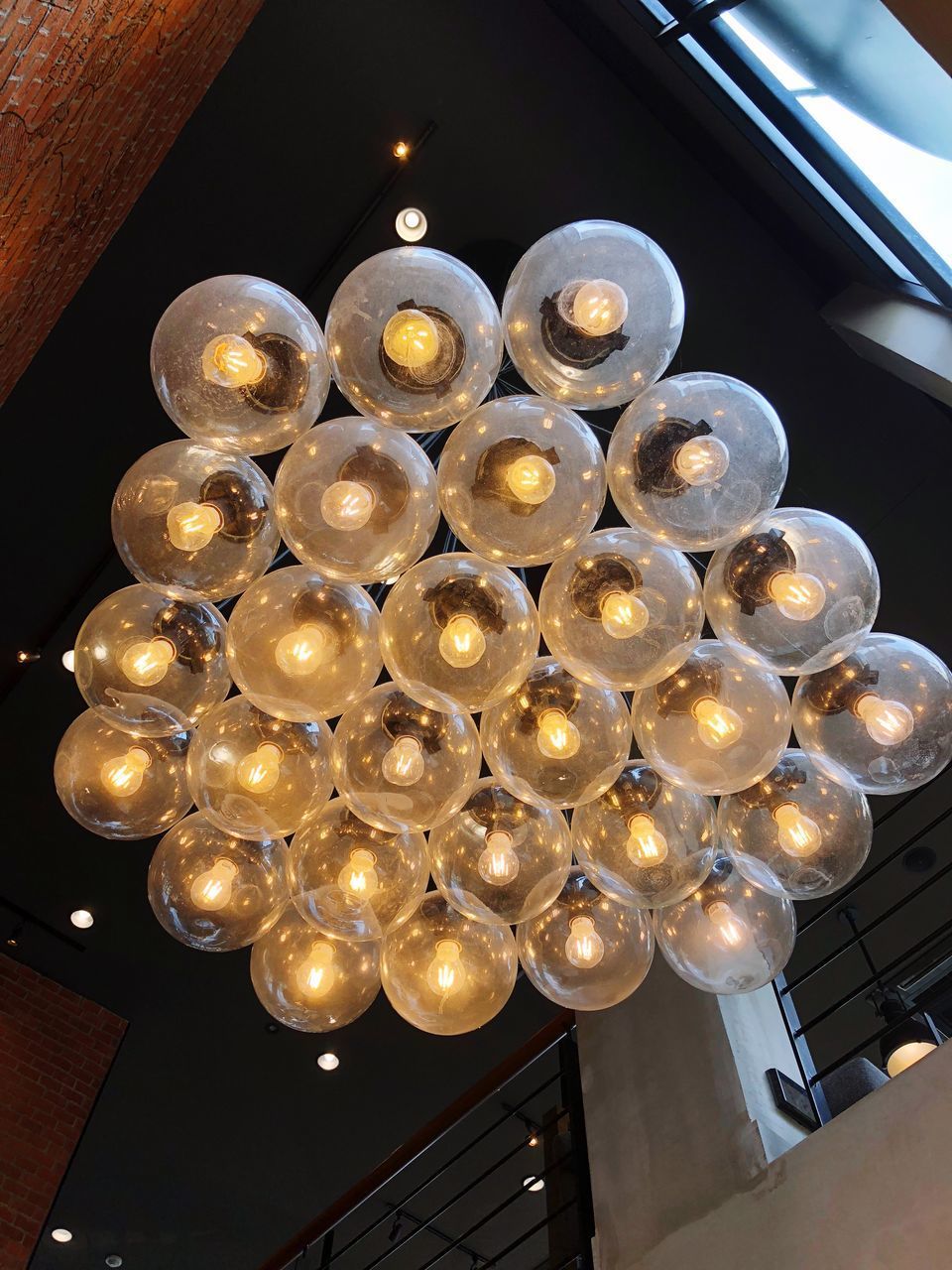LOW ANGLE VIEW OF ILLUMINATED PENDANT LIGHTS HANGING FROM CEILING