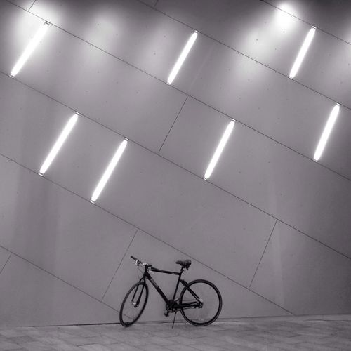 Bicycle parked against illuminated wall