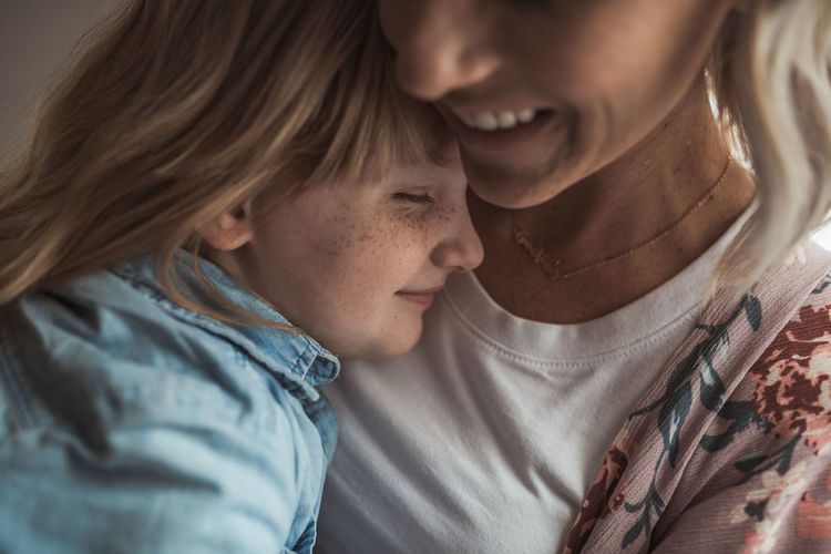 Close up detail of freckled girl being embraced by beautiful mother