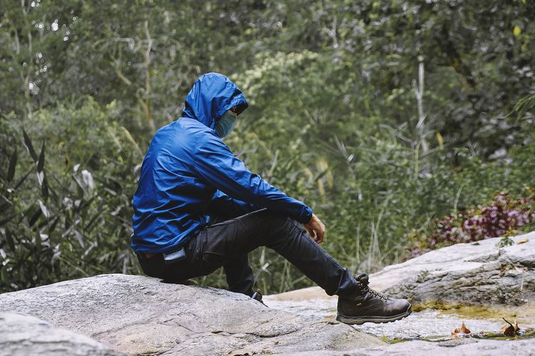 Man sitting on rock in forest