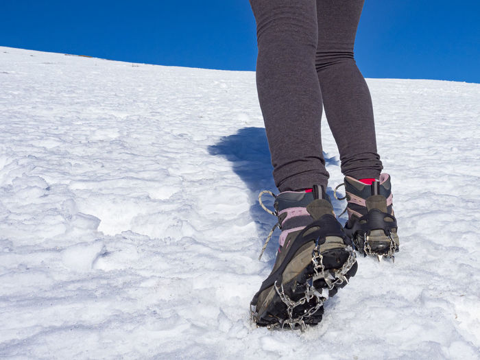 Woman hiker on a glacier with crampons on boots