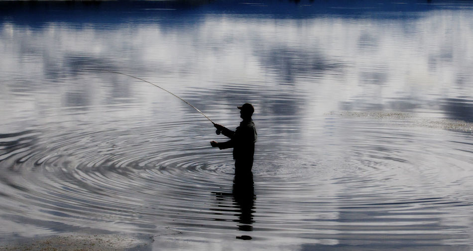 Man fishing while standing in lake