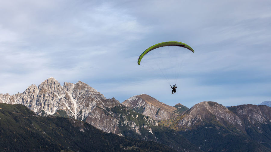 People flying by mountain against sky