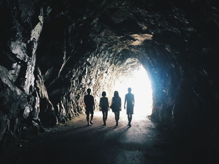 Rear view full length of friends walking in tunnel