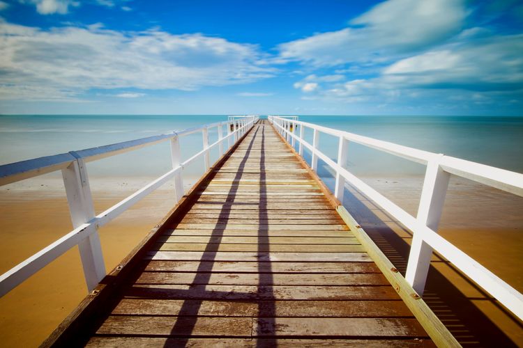View of wooden bridge over sea against sky