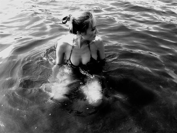 High angle view of sensuous woman in bikini sitting in sea
