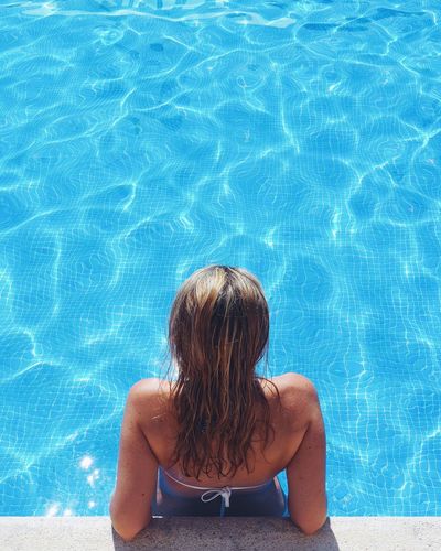 Rear view of woman relaxing in swimming pool