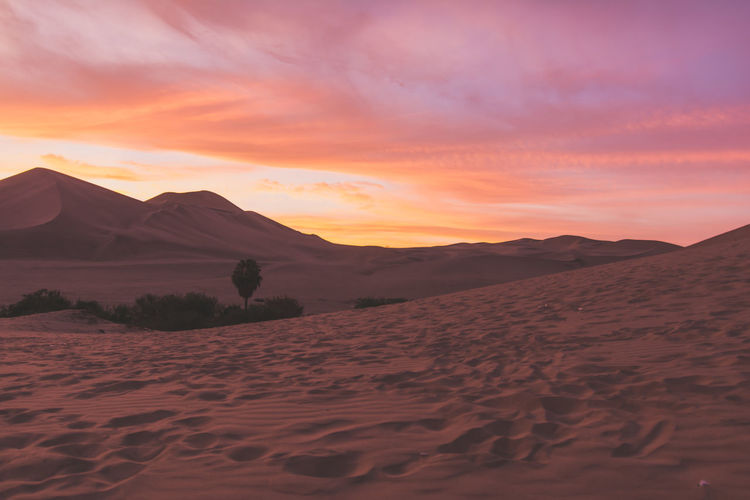 Sand dunes in desert against cloudy sky