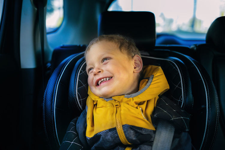 A joyful little boy smiles in a child's car seat. child safety when driving.