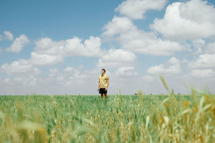 Rear view of woman walking on field against sky