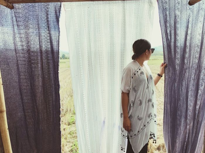 Woman standing by curtains on field