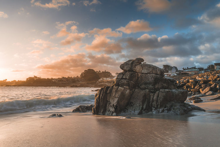 Rock formation on beach against sky during sunset