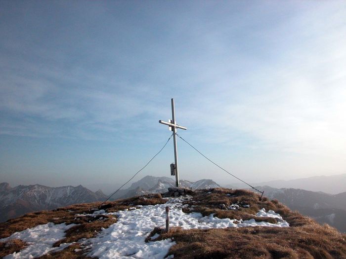 Summit cross in winter season, snow and sun on the mountain top