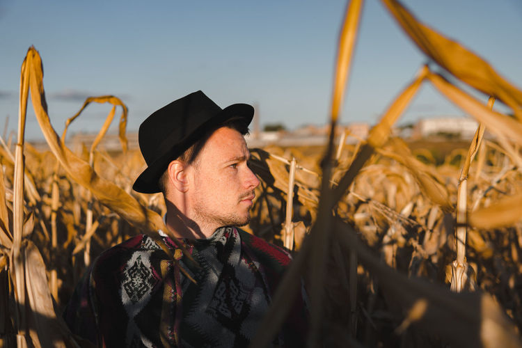 Male person wearing hat in a corn field, rural scene