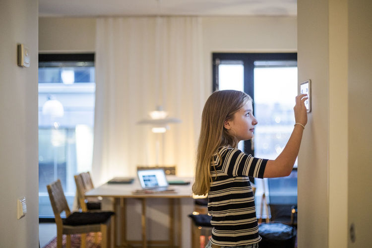 Girl with long hair using digital tablet mounted on wall at home