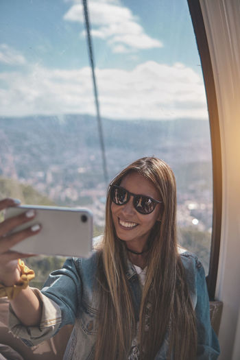 Young tourist sitting on the cableway in caracas enjoying a photo taken on her smartphone. 