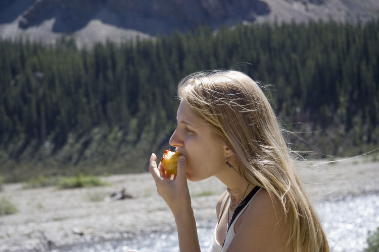 Close-up of young woman eating peach against trees at banff national park