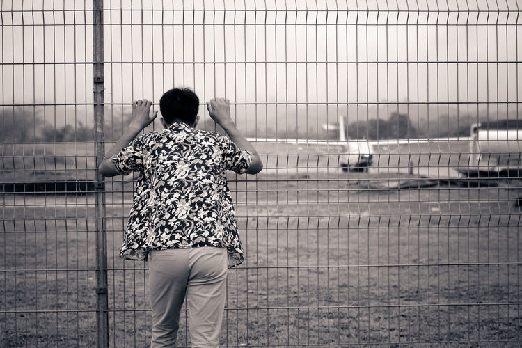Rear view of man standing by fence