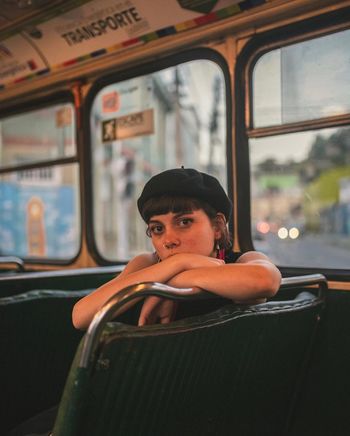 Portrait of woman sitting in bus during dusk