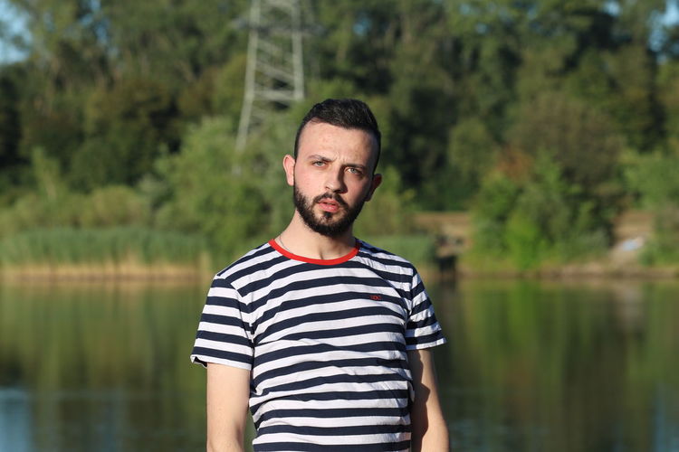Portrait of man standing against lake