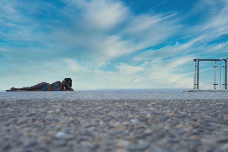Surface level of woman lying down on on floor against sky