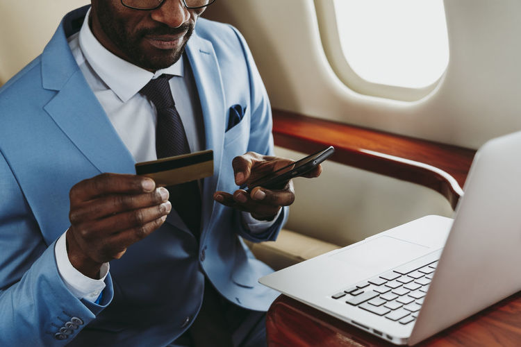 Male entrepreneur paying online through smart phone in private jet