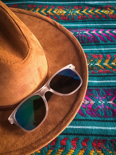 High angle view of sunglasses and hat on blanket