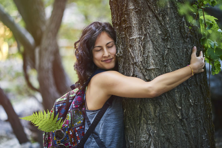 Young woman hugging a tree. she is happy.