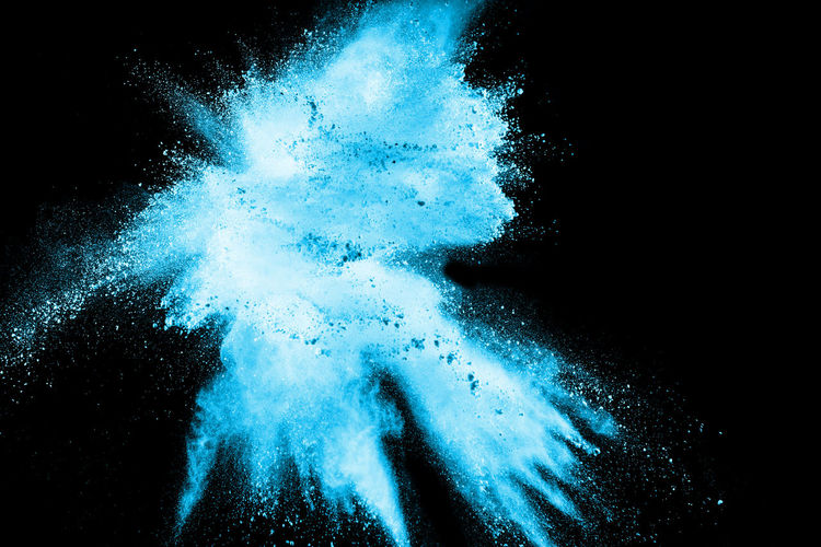 Defocused image of blue powder paints against black background