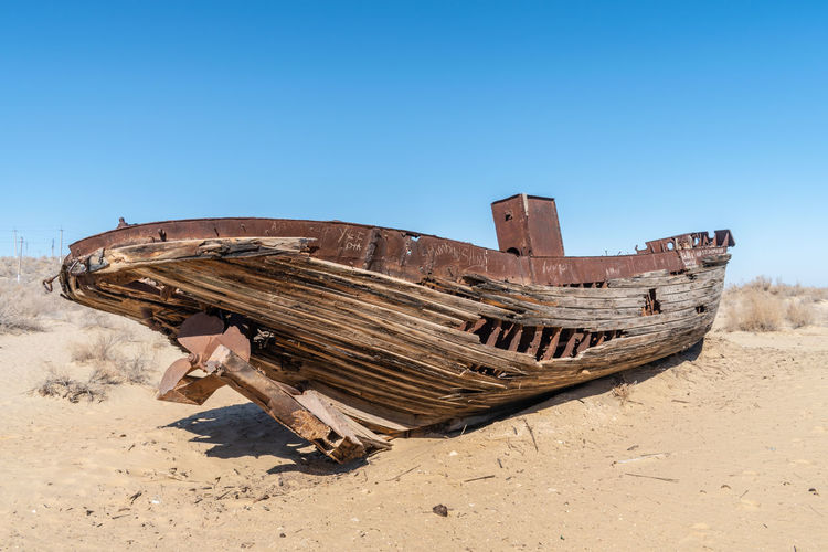 An abandoned ship against clear blue sky in what was once the aral sea, near moynaq, uzbekistan