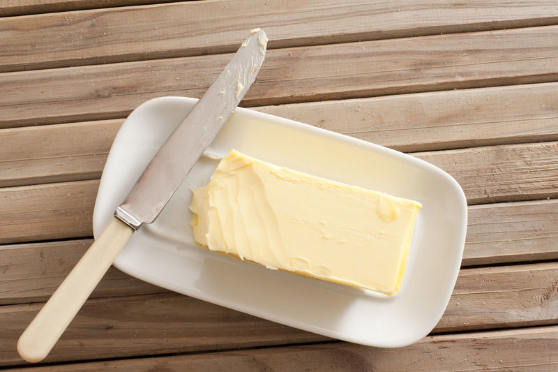 Directly above shot of butter and knife on wooden table
