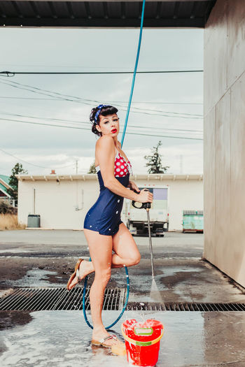 Woman working at a car wash wearing a one piece red white and blue swimwear 