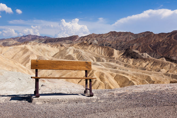 Bench on land against sky