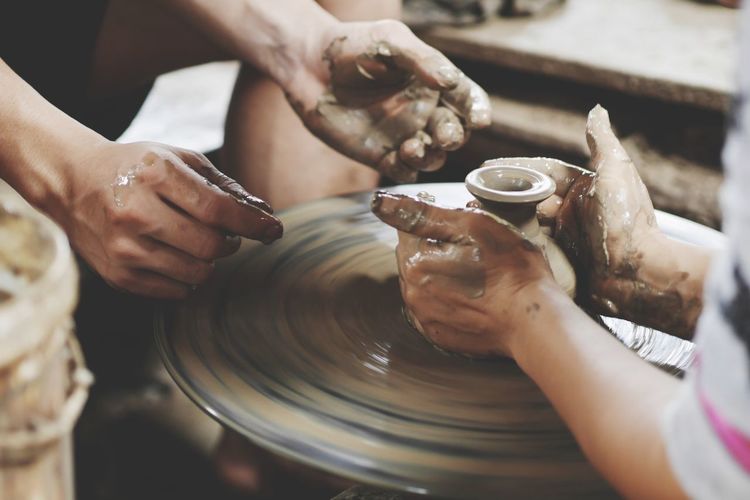 Cropped image of people working on pottery wheel