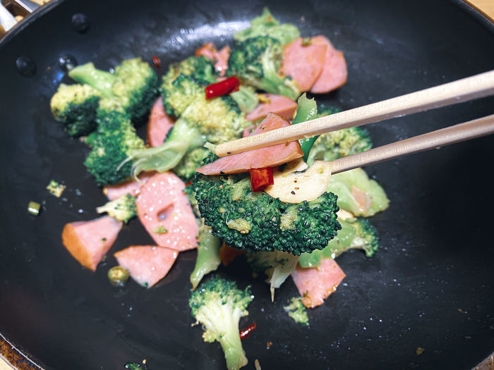 High angle view of food in cooking pan. broccoli , bacon , garlic and red chill peppers 